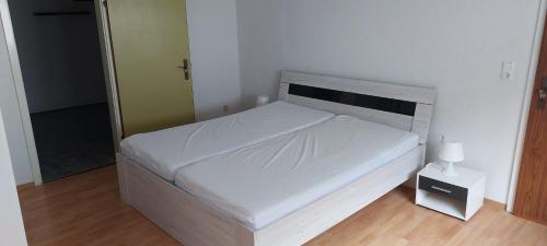 - une petite chambre avec un lit blanc et une table de nuit dans l'établissement Ferienwohnung Scheuern, à Gernsbach