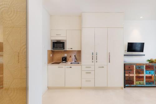 eine Küche mit weißen Schränken und einer Mikrowelle in der Unterkunft Optimum Apartment - Wolframplatz in Zürich