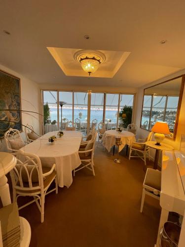 a dining room with tables and chairs and windows at Hôtel Le Roquebrune in Roquebrune-Cap-Martin