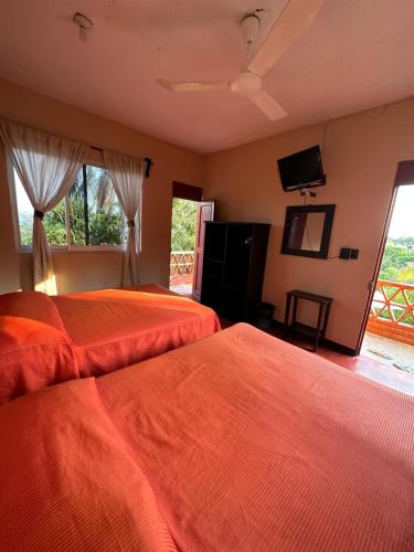 a bedroom with two beds and a flat screen tv at Hotel Cabañas Pepe in Puerto Escondido