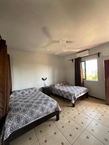 a bedroom with two beds and a window at Hotel Cabañas Pepe in Puerto Escondido