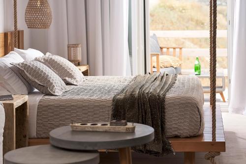 a bedroom with a swing bed with a table at Nirome Luxury Suites in Adamas