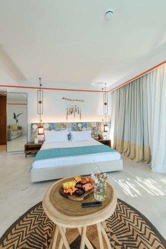 a large bedroom with a bed and a tray of food on a table at Folie Marine Hotel & Beach Club in Jal