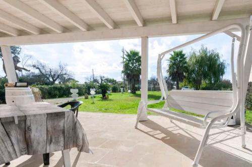 un columpio blanco en un patio con mesa en Villa delle Stelle con piscina, en Leverano
