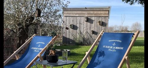 2 Gartenstühle und ein Tisch im Garten in der Unterkunft Le Clos de la Morière in Mont-Dol