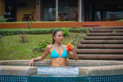 a woman in a swimming pool holding a drink at Hotel Villa Florencia in Turrialba