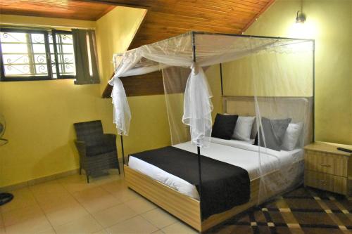 um quarto com uma cama de dossel e uma cadeira em Ezeife Guesthouse em Kampala