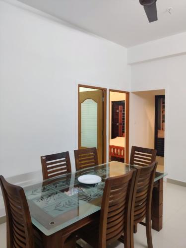 uma sala de jantar com uma mesa de vidro e cadeiras em Spacious 2BHK Near Airport em Cochin