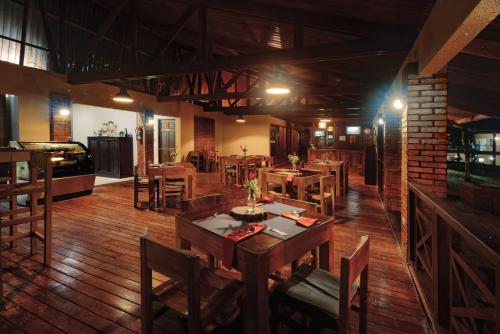 a restaurant with wooden floors and wooden tables and chairs at Hotel Villa Florencia in Turrialba