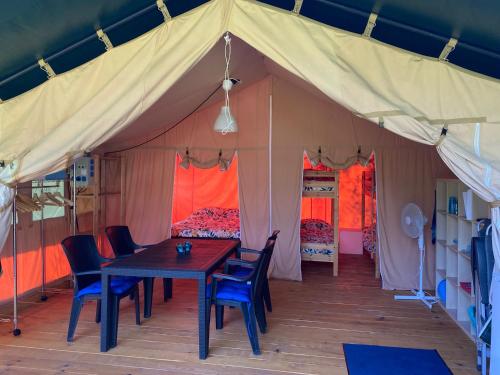een tent met een tafel, stoelen en bedden bij Safari tent in Magyarhertelend