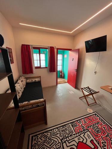 ein Wohnzimmer mit einem Sofa, einem TV und einem Teppich in der Unterkunft Pousada Bat N Breakfast No Beco do Batman in São Paulo