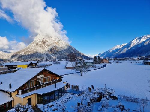 a snow covered mountain in front of a house at SALZANO Hotel - Spa - Restaurant in Interlaken