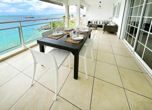 een eetkamer met een tafel en uitzicht op de oceaan bij Appartements T3 standing Vue mer époustouflante à quelques pas de la plage in Les Trois-Îlets