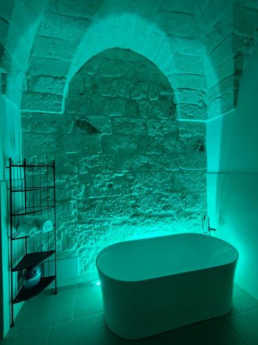 bañera en una habitación con pared de piedra en Le Pietre Apartments, en Ostuni