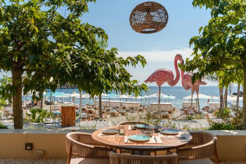 a table with chairs and flamingos on the beach at Folie Marine Hotel & Beach Club in Jal