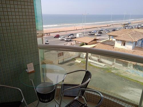 balcón con mesa y sillas y vistas a la playa en Flat na orla de Salvador, en Salvador