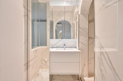une salle de bain blanche avec un lavabo et un miroir dans l'établissement Terrasse au coeur du Marais, à Paris
