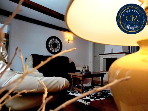 a living room with a couch and a table with a lamp at Carpathia Magic -adults only in Peştera
