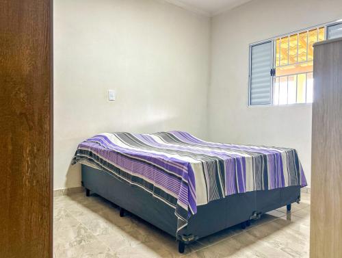 Un dormitorio con una cama con una manta a rayas. en Otima chacara c Wi-Fi e churrasq em Socorro SP, en Socorro