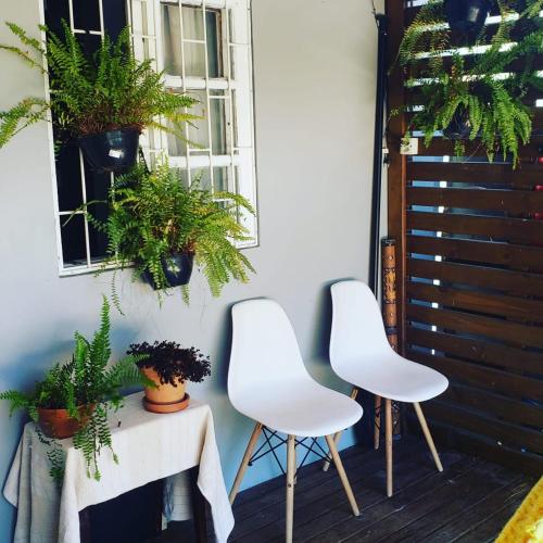 dos sillas blancas sentadas junto a una mesa con plantas en Linda Casa Inteira c/ Acesso a Praia do Campeche en Florianópolis