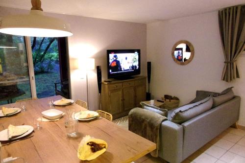 - un salon avec une table, un canapé et une télévision dans l'établissement Beautiful 3 rooms with terrace near the ocean, à Moliets-et-Maa