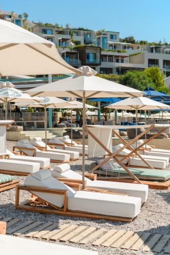 a group of lounge chairs and umbrellas on a beach at Folie Marine Hotel & Beach Club in Jal