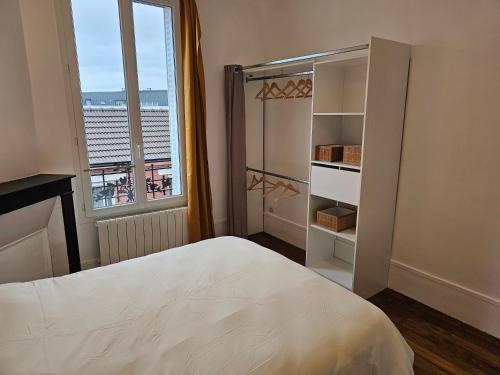 een slaapkamer met een wit bed en een raam bij Le Weber-Paris in Pantin