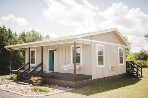 a tiny house with a porch and a green door at Nordins Hidden Hillside Cabin in Dardanelle