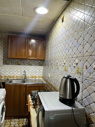 a kitchen with a tea kettle on top of a microwave at Tanih's Lodging in Abu Dhabi