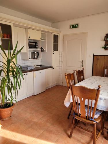a kitchen and dining room with a table and chairs at Tótvár lovarda szálláshely in Kővágótőttős