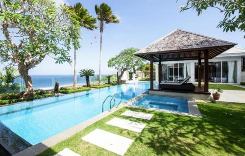 a swimming pool with a gazebo next to the ocean at Cliff Front pandawa Beach Karang Kembar 5 in Ungasan