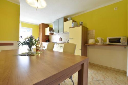 a kitchen with a wooden table and yellow walls at Reihenferienhaus mit Kamin und Terrasse im Ostseeland OFC 11 in Gerdshagen