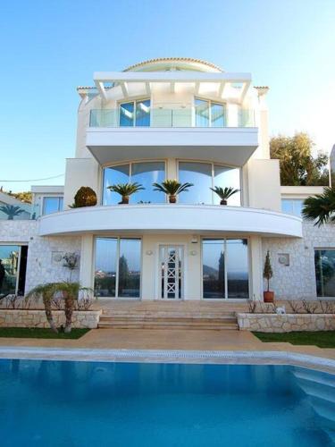 a large house with a swimming pool in front of it at Luxurious Family friendly Villa Anavyssos in Anavissos