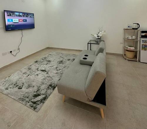 Cozy apartment in AlOlaya Khobar في الخبر: غرفة معيشة مع أريكة وتلفزيون