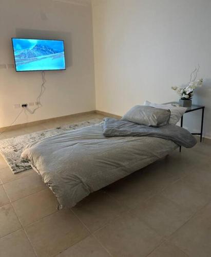 Cozy apartment in AlOlaya Khobar في الخبر: سرير في غرفة نوم مع تلفزيون على الحائط