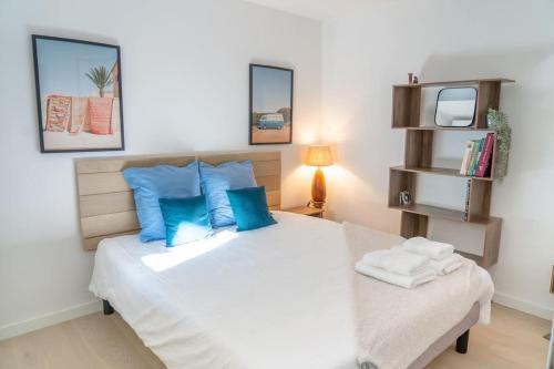 une chambre avec un grand lit blanc avec des oreillers bleus dans l'établissement Appartement Terrasse et Parking, à Aix-en-Provence