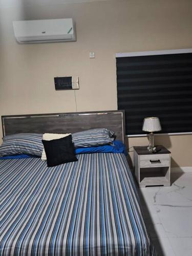 a bedroom with a striped bed with a night stand at KC suites in Government Pen