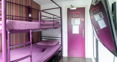 two bunk beds in a pink room with a door at Safestay London Kensington Holland Park in London