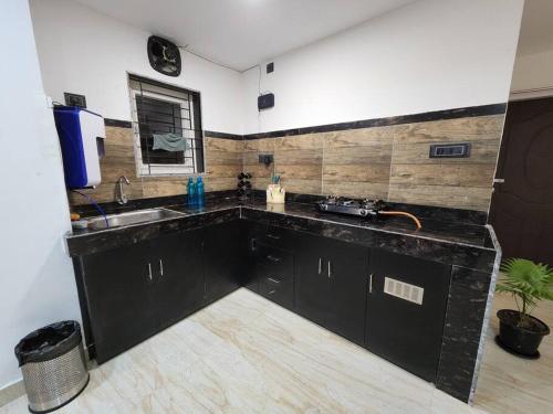a kitchen with black cabinets and a sink at Lily Homes in Guwahati