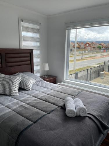 a bedroom with a large window with towels on a bed at Departamento manantiales 1 in Punta Arenas