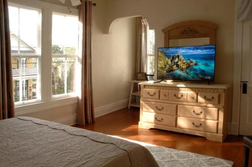 MayLi Place Luxury King Suite Downtown St Augustine في سانت أوغيستين: غرفة نوم مع تلفزيون فوق خزانة