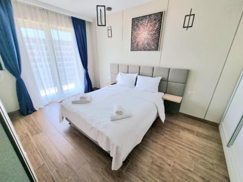 Un dormitorio con una gran cama blanca y una ventana en Apartament Best View - Endless Summer Mamaia Nord Apartaments, en Mamaia Nord – Năvodari