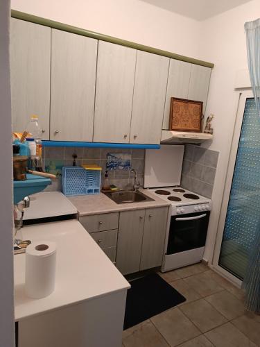 a kitchen with white cabinets and a sink and a stove at Villa Stella-Maria in Paralía Avdhíron