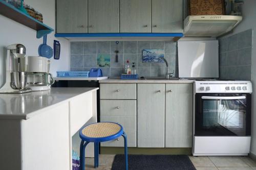 a kitchen with white cabinets and a blue stool at Villa Stella-Maria in Paralía Avdhíron