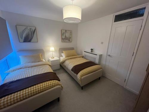a bedroom with two beds and a white door at Modern and Comfortable Flat with private parking in Oxford