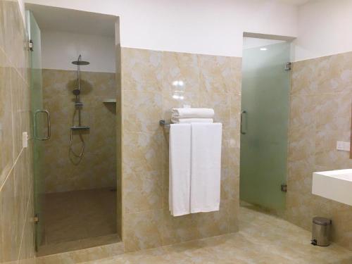 a bathroom with a shower and a sink and towels at Samsara in Galle