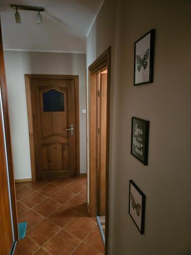 a hallway with a door and pictures on the wall at Apartament blisko jeziora in Ełk