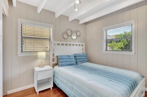 a bedroom with a bed and two windows at Sunny Naples - Subtropical Oasis Cottage in Naples