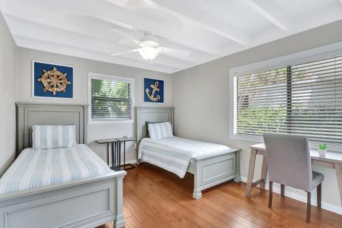 a bedroom with two beds and a desk and a window at Sunny Naples - Subtropical Oasis Cottage in Naples