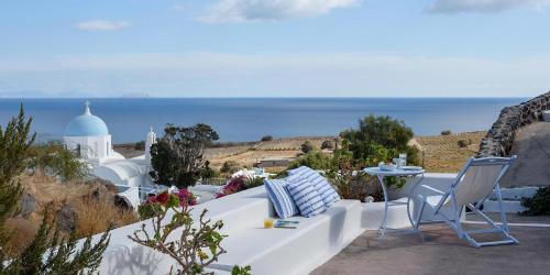a white bench with chairs and a view of the ocean at Aghios Artemios Traditional Houses in Imerovigli